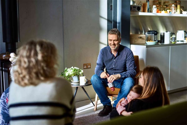 Man on sofa surrounded by friends
