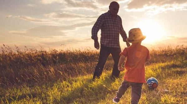Grandad and grandson playing football together