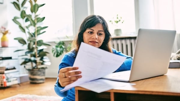 Woman looking at paperwork and laptop