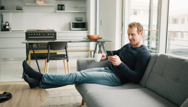Man lying on sofa looking at his mobile phone