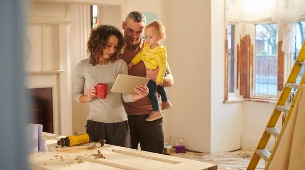 family standing in a new home looking at plans on a tablet